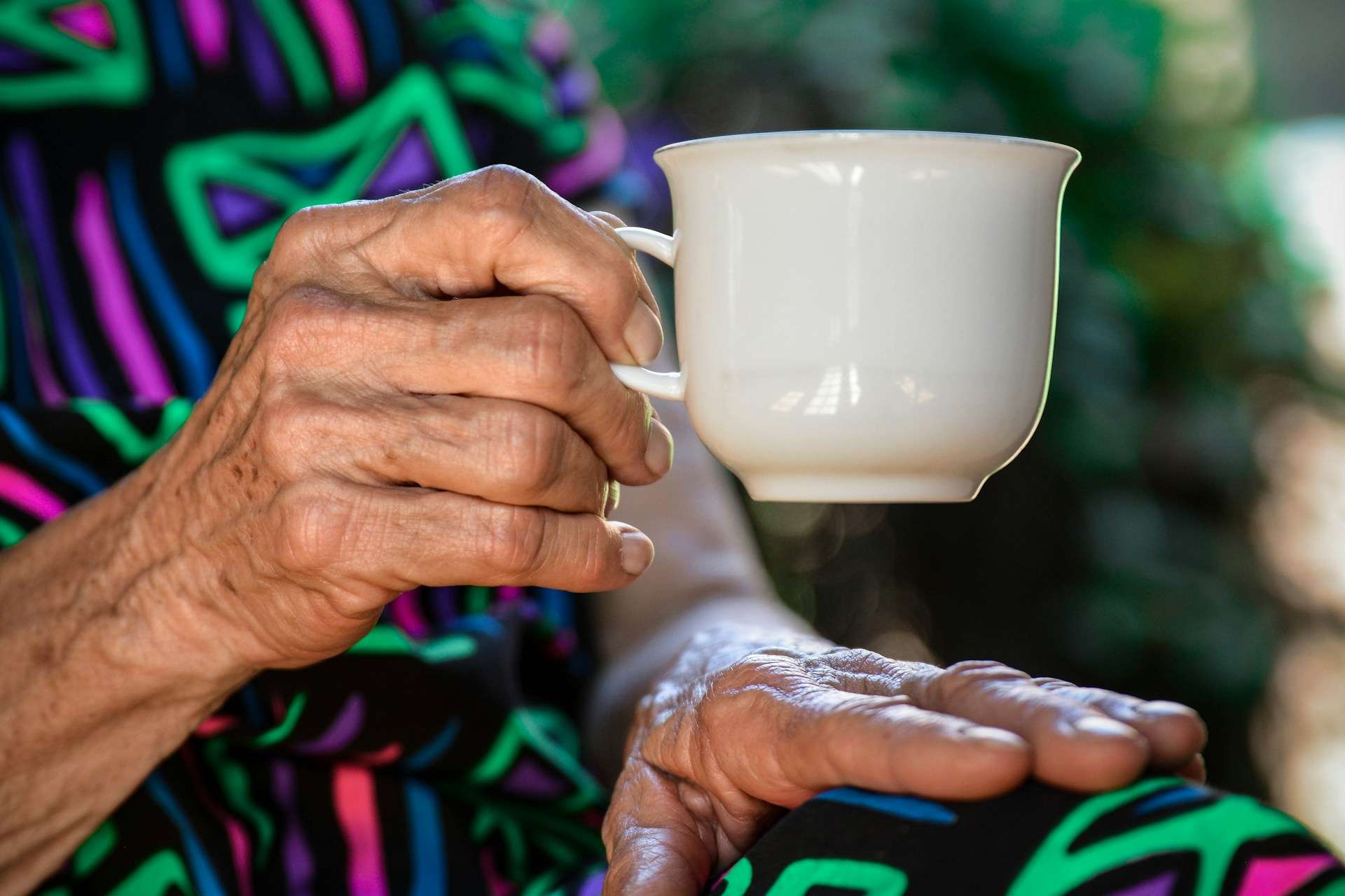 Older person drinking tea with milk alongside “Healthy ageing with dairy” fact sheet highlighting reduced falls and fracture risk in aged care.